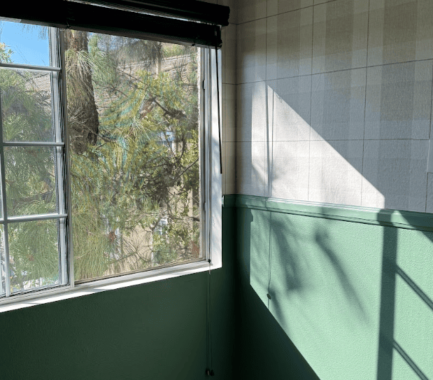 Professional wallpaper installer from CoverUp Services evaluating a living room wall, taking measurements and inspecting surface conditions during the first visit